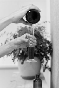 Naturopath pouring a supplement into a measuring tube.